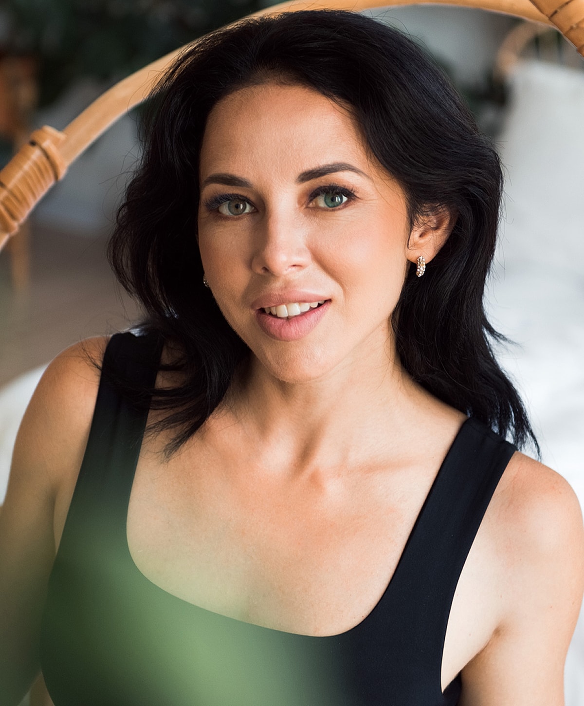 Woman with dark hair smiling in natural light.