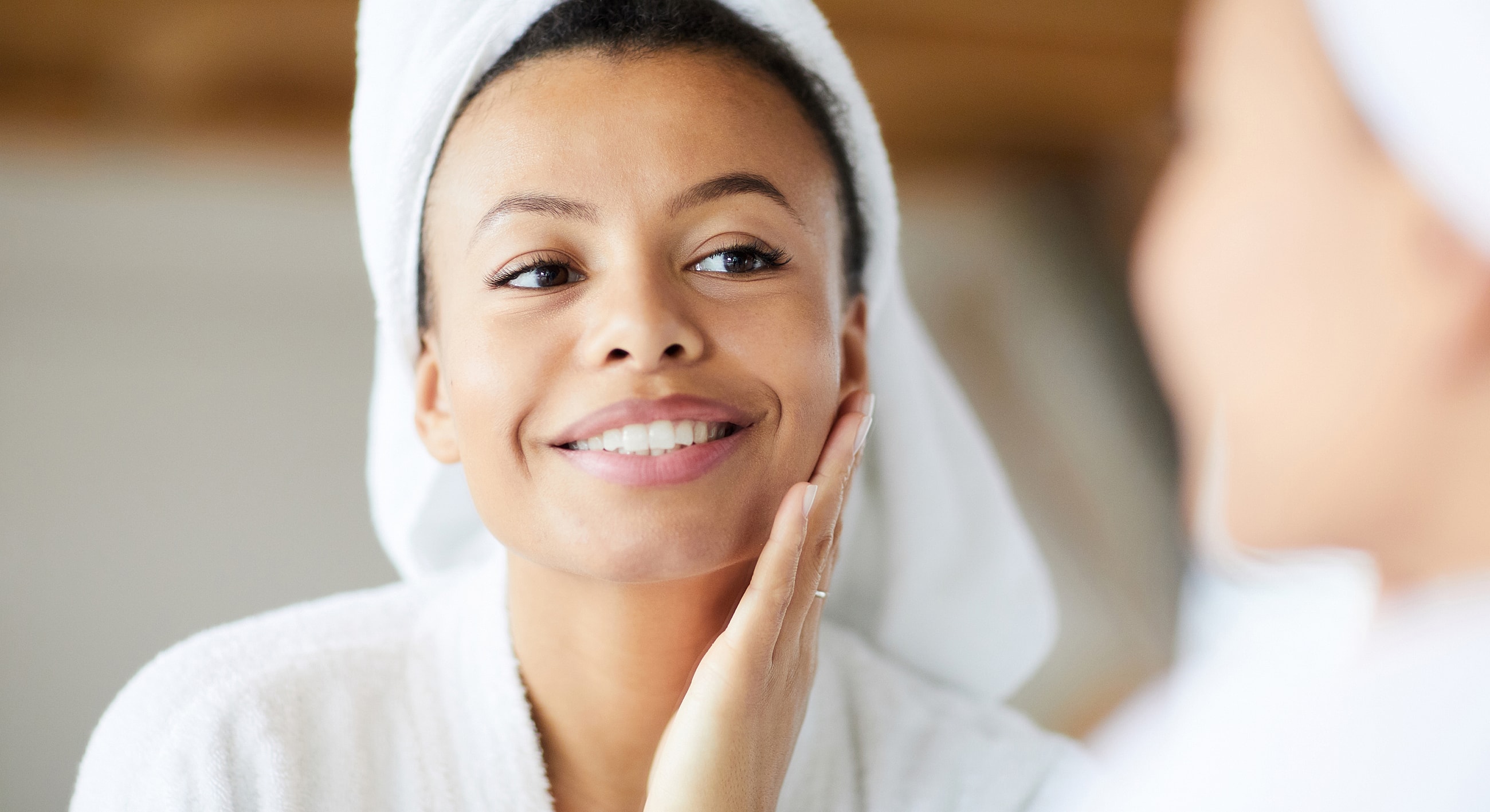Smiling woman with towel enjoying skincare routine.